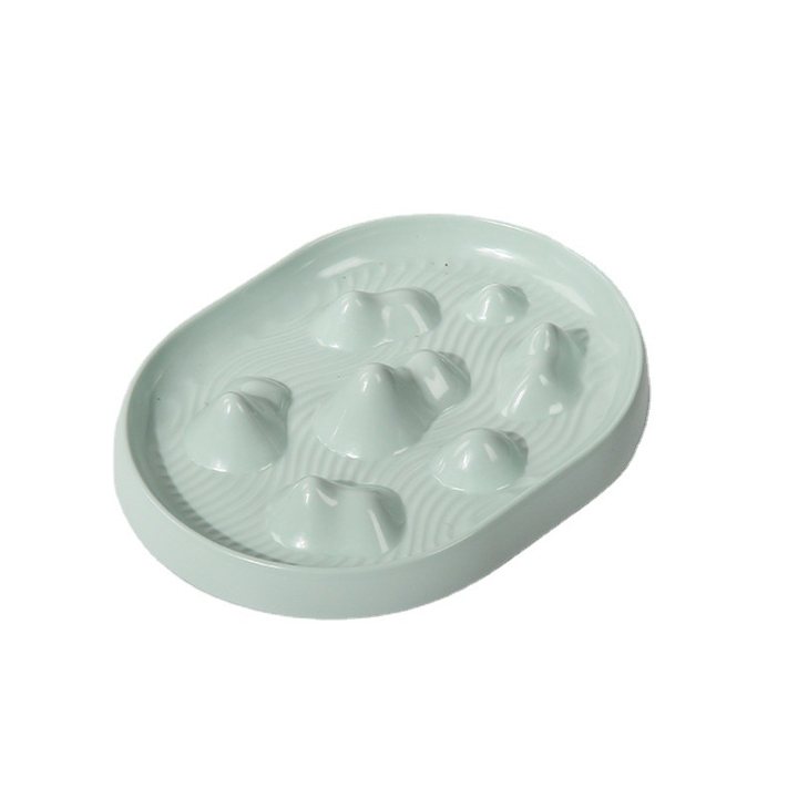 Oval slow-feeder pet bowl with raised cone-shaped ridges in a pale green finish.