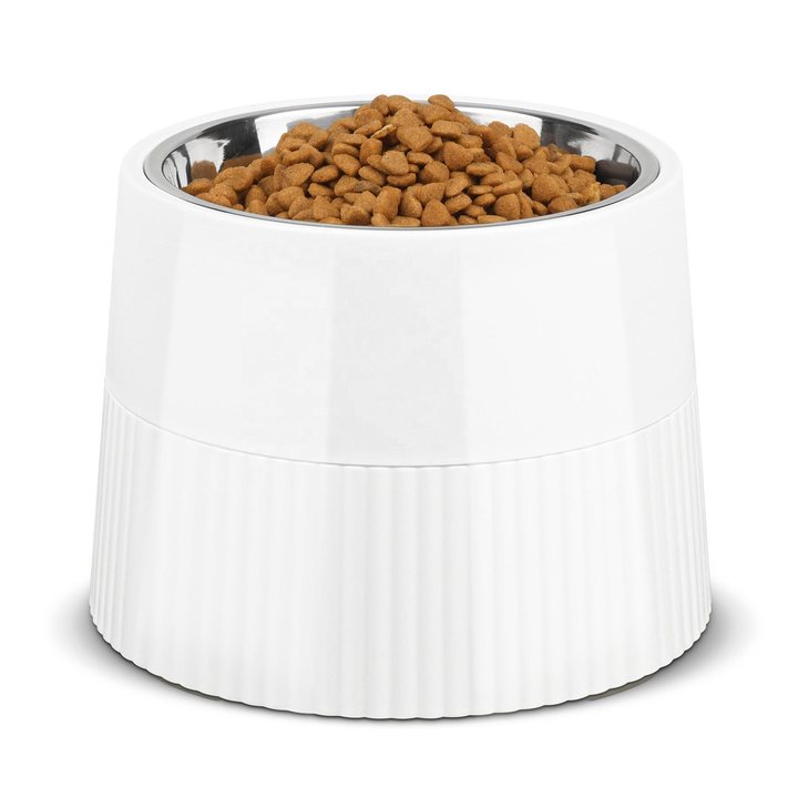 White ribbed elevated pet bowl stand with a removable stainless steel liner, filled with dry kibble.