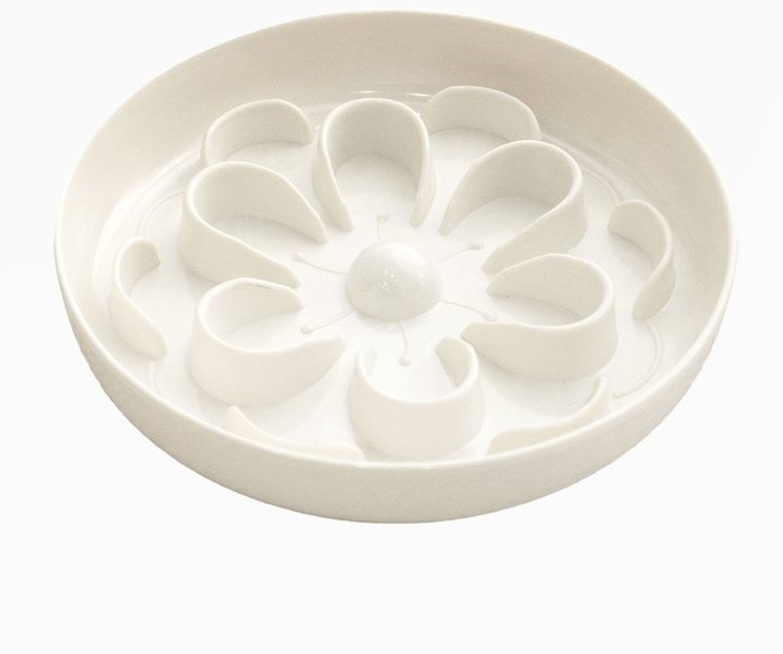 White ceramic pet feeding bowl molded with a raised flower pattern of eight curved petal-shaped ridges around a central raised dome, angled three-quarter view against a plain white background.