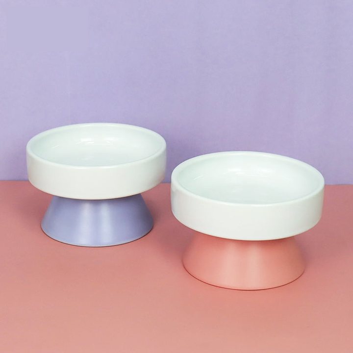Two ceramic pedestal bowls, lavender and pink, on a lilac-over-pink styled backdrop