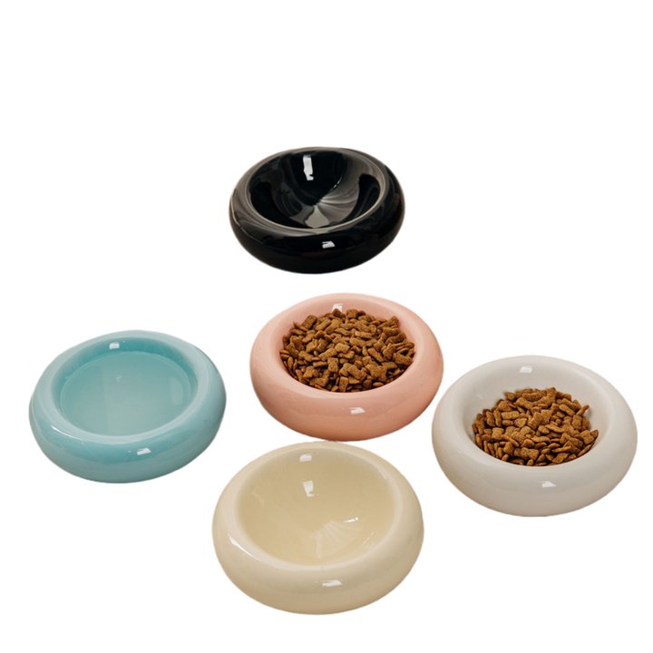 Donut-shaped ceramic pet bowls in black, pink, teal, cream, and white