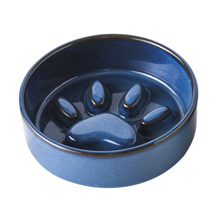 Blue ceramic slow feeder bowl with a moulded paw-print relief inside.