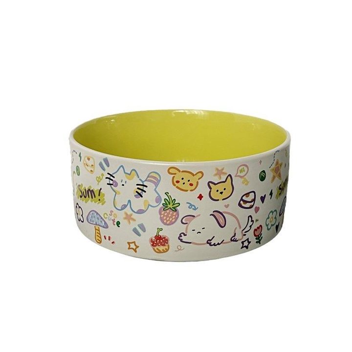 Ceramic pet bowl with a cream exterior featuring a colourful cartoon doodle print and a bright yellow glazed interior.