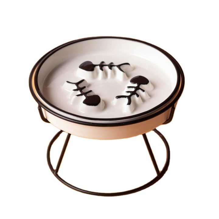 Cream ceramic slow-feeder dish with a fishbone relief pattern, set on a black iron ring stand.