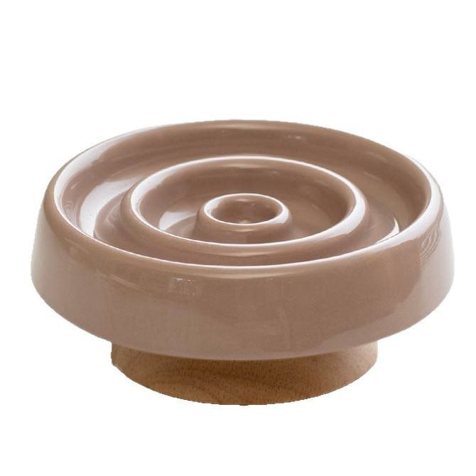 Taupe ceramic slow-feeder bowl with a concentric ring pattern, set on a wooden base.