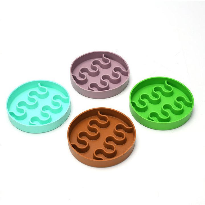 Four round silicone slow-feeder mats with a wavy maze pattern, in mint, mauve, green and brown.