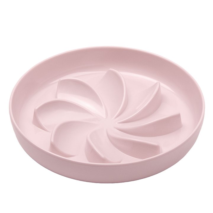 Pale-pink ceramic slow-feeder bowl with a pinwheel-shaped ridge pattern.