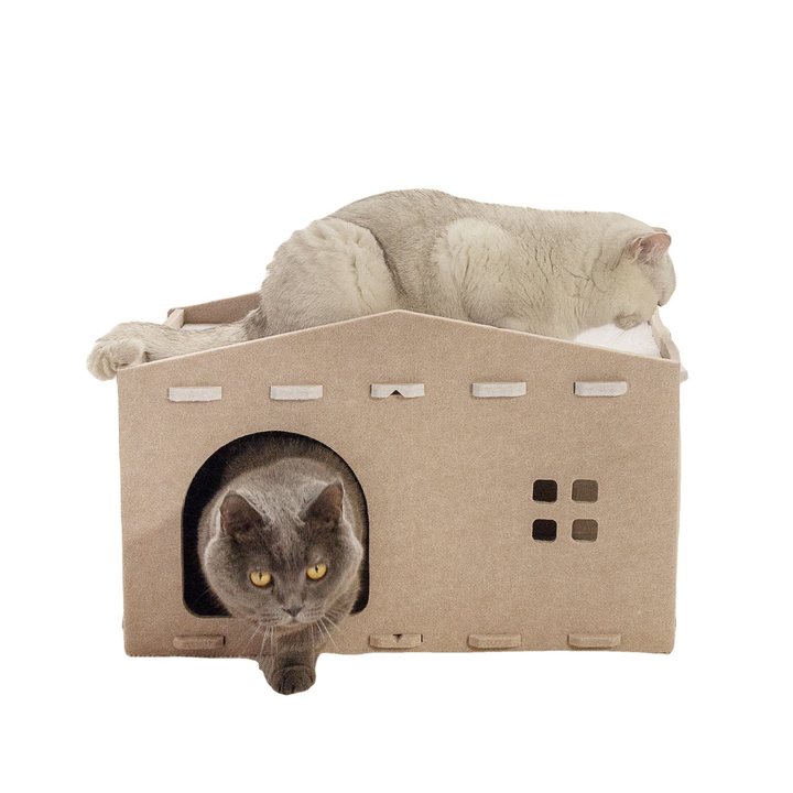 Tan felt cottage-shaped folding cat house with a peaked roof, square window accents, and a round entrance hole.