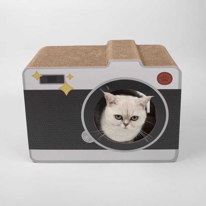 Camera-shaped cardboard cat scratcher house with a round lens entrance, studio shot