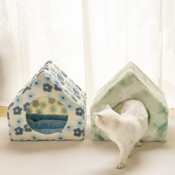Two peaked plush cat houses, one cream with a blue floral print and one mottled green, round doorway
