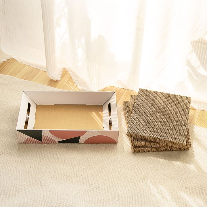 Cardboard cat scratcher tray with a geometric-print exterior, shown with a stack of replacement scratch-pad inserts