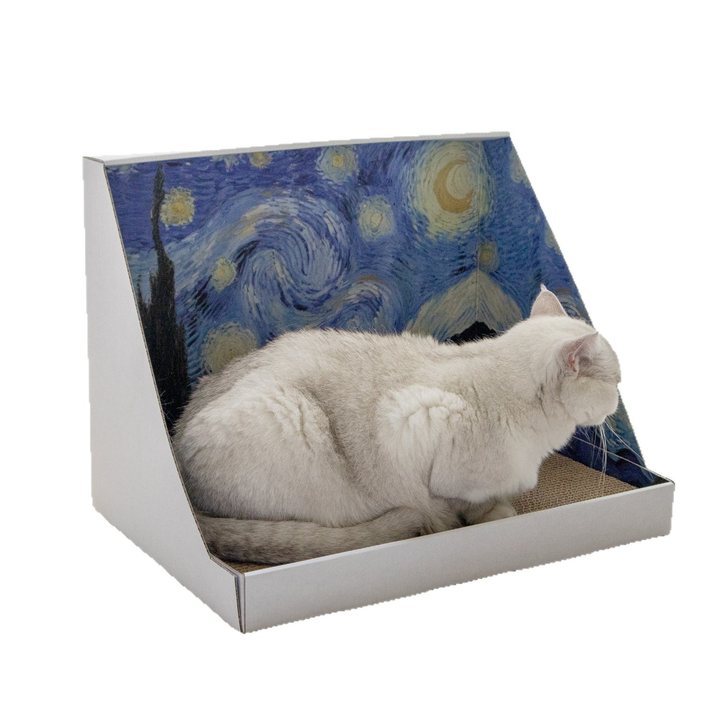 Cat lounging in a slant-backed cardboard scratcher chair printed with a swirling night-sky pattern.