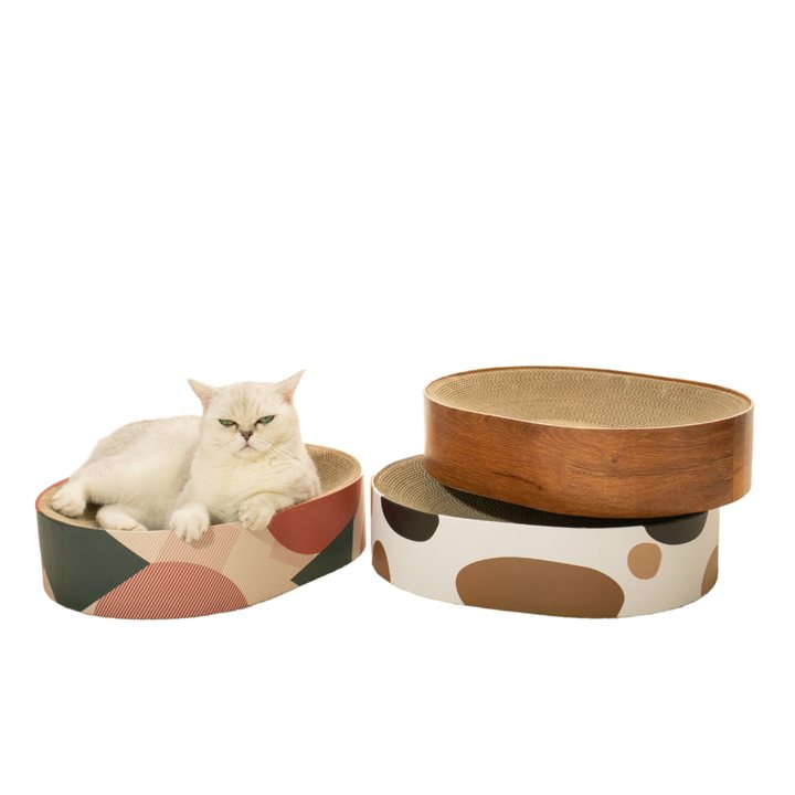 Two oval cat scratcher boxes in different printed finishes, one with a wood-grain scratch pad visible inside.