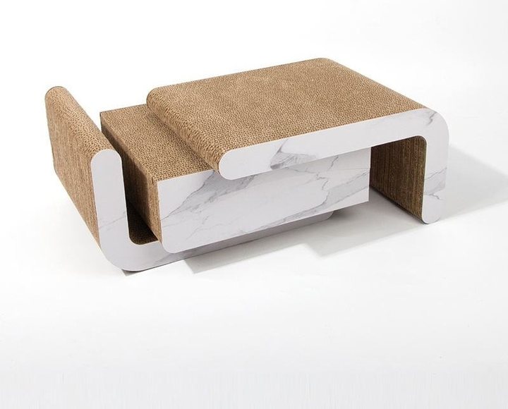 A low, curved coffee-table-style cat scratcher with a white marble-pattern laminate frame and a natural brown corrugated-cardboard scratch surface on the raised seat and side panel, set against a plain white background.