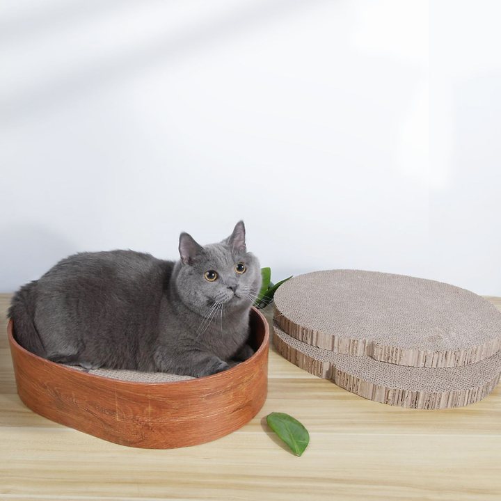 Round wood-grain-print cat scratcher nest bowl on a wooden tabletop with spare round refill pads nearby.