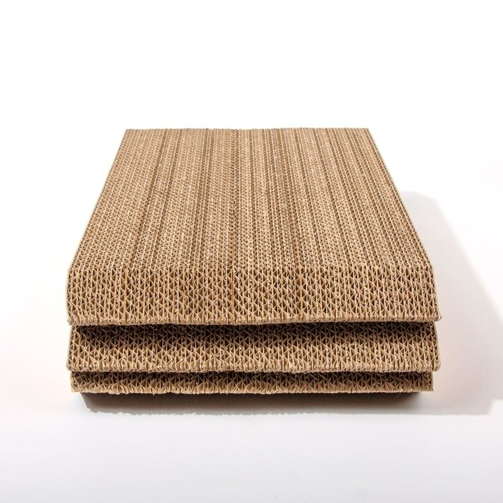 Three flat rectangular panels of natural kraft-brown corrugated cardboard, stacked and shown edge-on to display the fluted internal ridge pattern, resting on a plain white surface.