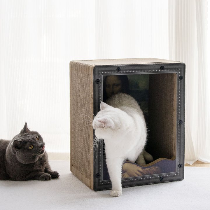 Cube-shaped corrugated cardboard cat scratcher box with a studded picture-frame front panel printed with a classical portrait painting