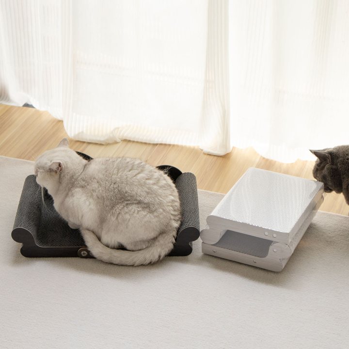 Two low wood-framed cat scratcher lounges with scalloped ends, one with a black corrugated pad and one with a white corrugated pad