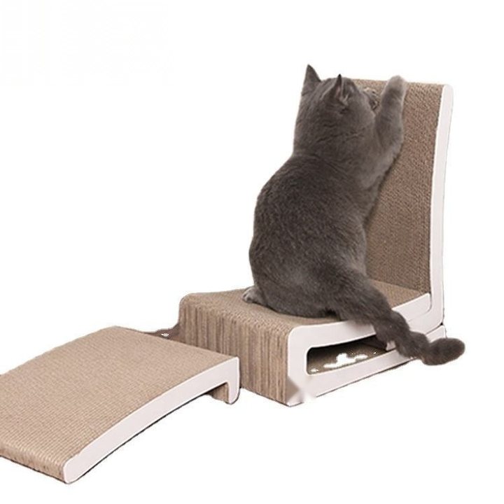 A grey cat sitting on a beige woven cat scratcher/lounge unit with a white frame, one paw raised against the tall scratch-pad backrest, beside a matching low ramp accessory, against a plain white background.