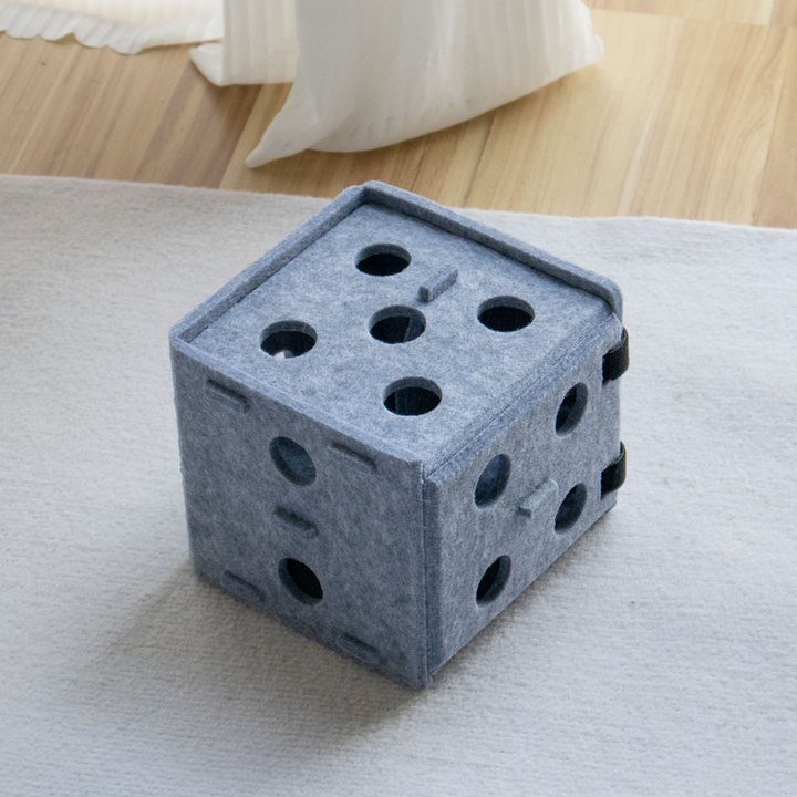 Grey felt dice-shaped cat puzzle box with circular cut-out holes.
