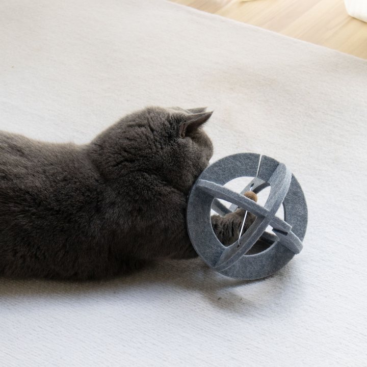 Close-up of a grey felt lattice-ball cat toy with a wooden bead inside